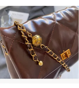Detailed macro of dark brown quilted leather texture with gold metal chain strap