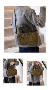 Detail of olive green suede Boston bag featuring dual handles and adjustable shoulder strap
