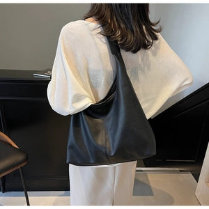Detail of black large-capacity tote bag in pebbled leather finish on a shoulder model