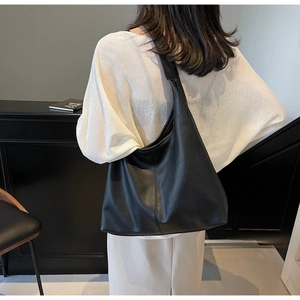 Close-up of a black lychee texture leather shoulder tote bag shown on a model's shoulder