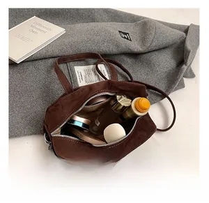 Detail view of large interior space in brown suede handbag with cosmetics and striped lining