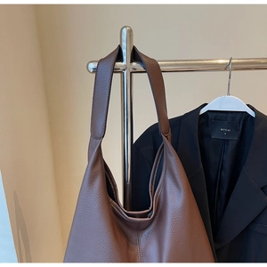 Détail du sac cabas en cuir grainé marron montrant la texture souple et la bandoulière hobo