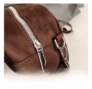 Macro detail of silver-toned metal zipper and D-ring on brown suede leather handbag