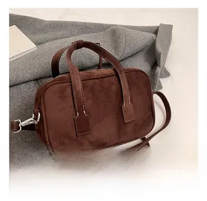 Detail shot of brown matte suede handbag with contrast stitching on grey coat