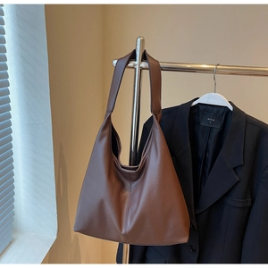Vue détaillée du grand sac hobo marron foncé avec texture cuir grainé sur un cintre
