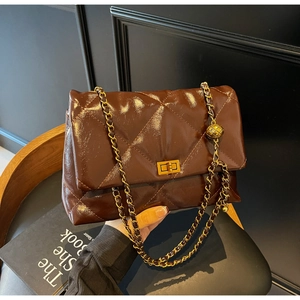 Close-up of quilted coffee leather shoulder bag with golden ball chain and twist lock