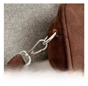Close-up of premium silver metal spring hook and fine stitching on dark brown suede bag