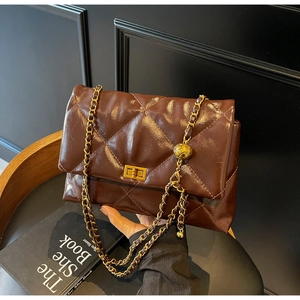 Close-up of dark brown quilted leather bag with gold chain and metal turn-lock detail