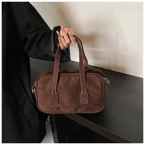 Detail of dark brown suede Boston bag featuring white contrast stitching and D-ring