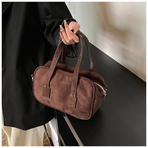 Detail of dark brown matte suede handbag with contrast stitching and metal zipper