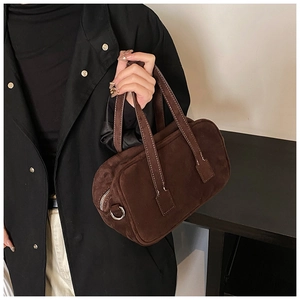 Close-up of matte dark brown suede boston bag with detailed stitching and silver hardware