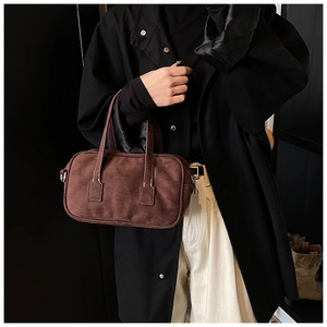 Detailed view of matte brown suede texture and fine stitching on a vintage handbag