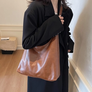 Brown leather large capacity tote bag shown on model with minimalist stylish design