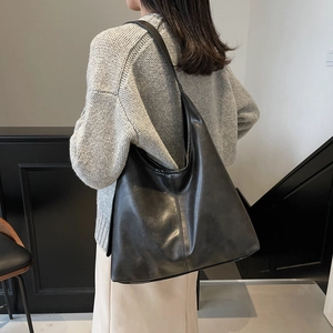 Minimalist black leather tote bag for women showing a stylish shoulder carry on model