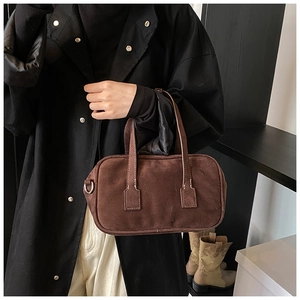 Detailed view of a vintage dark brown matte Boston bag styled with a long black trench coat