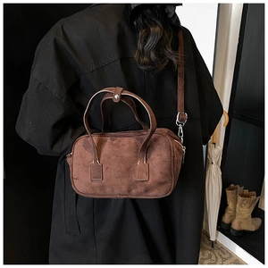 Detailed close-up of brown suede Boston bag featuring reinforced handles and soft texture