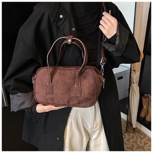 Detail of dark brown matte Boston bag showing texture and top handle snap fastener