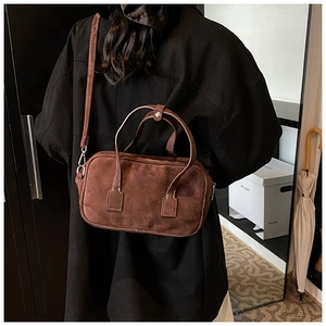 Detail of a dark brown suede handbag with minimalist stitching and silver hardware