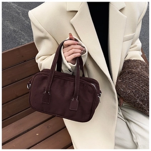 Detail view of a vintage dark brown suede Boston bag held by a model in a winter coat