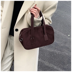Detailed texture of a vintage matte brown suede Boston bag held by a model