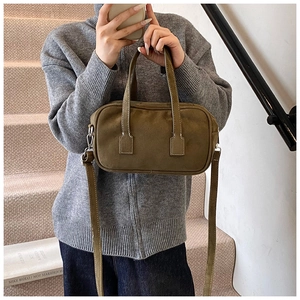 Detail of olive green suede handbag with square stitching and adjustable shoulder strap