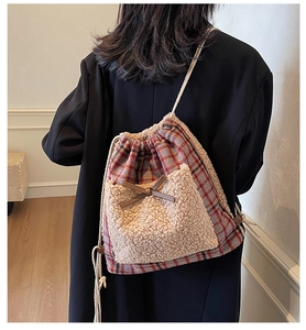 Détail du sac à carreaux avec poche en polaire beige et nœud décoratif marron foncé