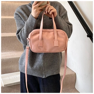 Pink matte Boston bag with top handles and adjustable strap on neutral steps