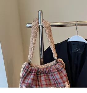 Détail du sac à carreaux avec une large bandoulière en peluche de couleur chameau