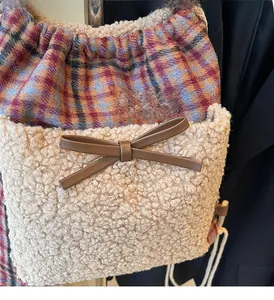 Détail du tissu à carreaux et fausse fourrure beige avec un nœud en cuir marron