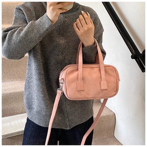Pink matte suede handbag with dual top handles and detachable shoulder strap on model