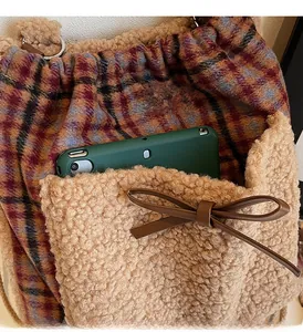Détail de la poche avant en laine d'agneau avec nœud en cuir sur un sac à main à carreaux