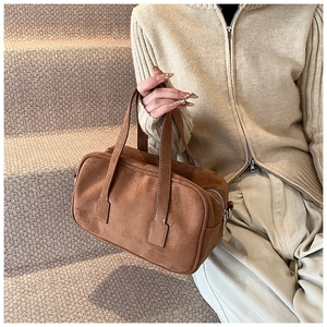 Brown frosted suede Boston bag with metal zipper and fine stitching in a lifestyle setting