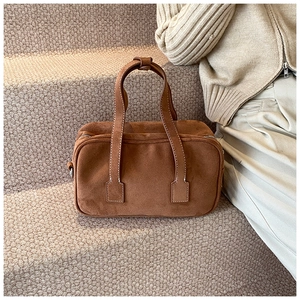 Macro detail of brown frosted suede texture and silver zipper on retro Boston bag