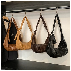 Macro detail of crescent croissant bags showing large knot straps and litchi grain leather