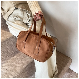 Detail of dark brown suede Boston bag showing matte texture and silver zipper accents