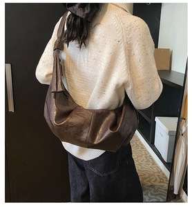 Deep brown crescent hobo bag with knotted strap detail shown on a female model