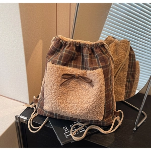 Détail du sac à cordon à carreaux avec poche avant en peluche et décoration de nœud