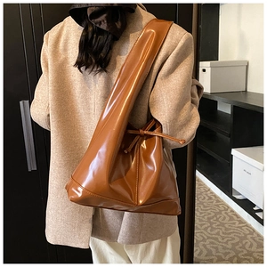 Close-up of caramel brown leather tote bag with functional drawstring detail on shoulder