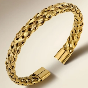 Close-up of golden braided stainless steel open bangle with smooth end caps and luxury texture
