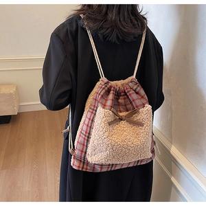 Détail d'un sac à dos à carreaux avec bordure en peluche et nœud en cuir sur mannequin