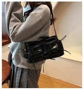 Chic black glossy shoulder bag with dual flap pockets shown on model in a casual outfit