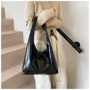 Close-up of black glossy hobo bag with delicate bow knot detail and polished finish