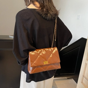 Caramel brown quilted crossbody bag with gold chain strap shown on person in classic style