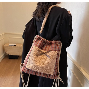 Détail du sac à dos à carreaux avec poche en polaire beige et nœud en cuir marron