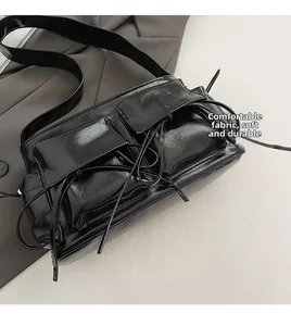 Detail of glossy black shoulder bag with dual pockets and stylish drawstring knots