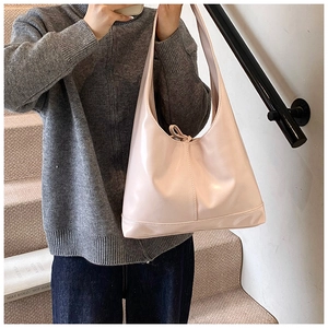 Close-up of pink glossy patent leather tote bag with stylish tie-knot detail on handle