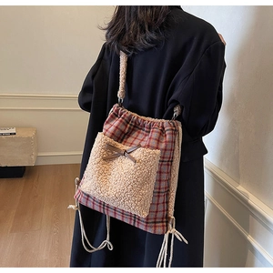 Détail du sac à cordon à carreaux rouges et bleus avec poche polaire et nœud en cuir
