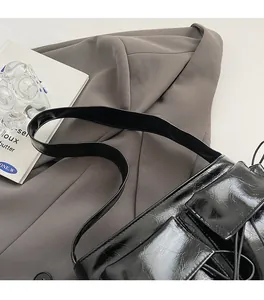 Detail of glossy pleated black shoulder bag with bow accents and comfortable wide strap