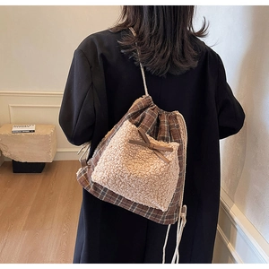 Détail d'un sac à dos à carreaux avec poche en peluche et nœud porté par un mannequin