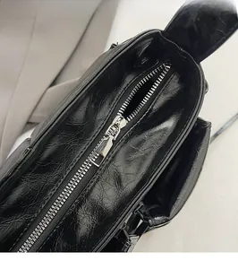 Close-up of smooth silver metal zipper and black crinkle leather texture on the handbag